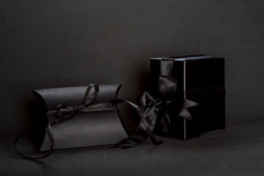 Two black gift boxes with black ribbon bow on dark background, copy space. Valentine's day, birthday romantic concept, greeting card.