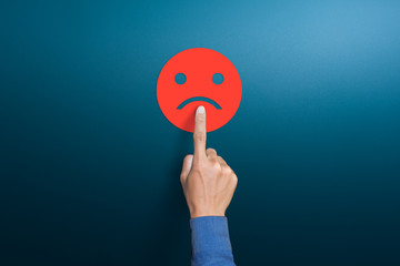 The client's hand choose the red sad face icon, Customer service evaluation, dissatisfaction in...
