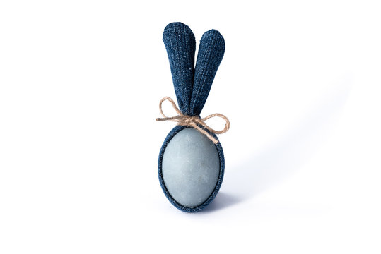 Easter egg with blue denim bunny ears on white background. DIY idea. Minimal happy Easter concept. Copy space