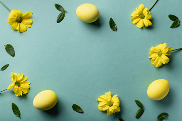 Naklejka na ściany i meble yellow eggs and flowers on a green paper background. Easter minimal card. flat lay, copy space.