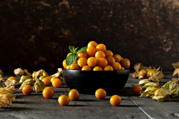 Fototapeta na wymiar Fresh Physalis, in a wooden bowl close up on a gray background. Image