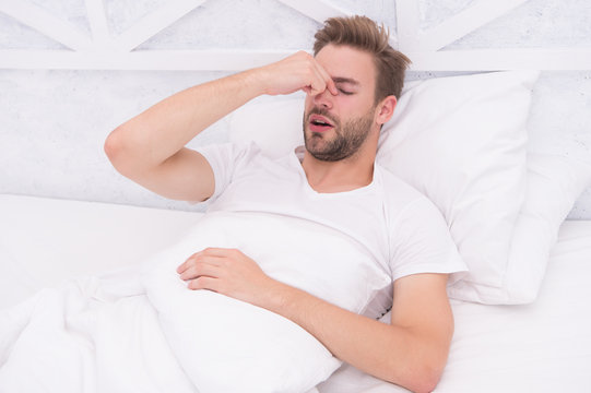 Snoring can increase risk headaches. Common symptom of sleep apnea. Causes of early morning headache. Migraine headaches. Sleep problems can lead to headaches in morning. Handsome man relaxing in bed
