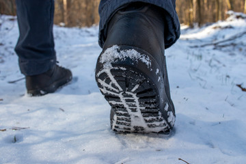 Men's legs in black boots, walk in the winter in the snow