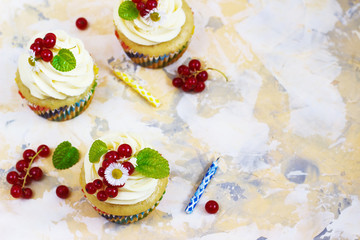 Gentle, festive cupcake with cream and berries nd a candle a light background