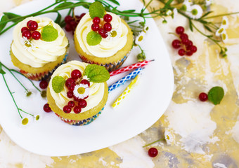 Gentle, festive cupcake with cream and berries аnd a candle a light background