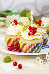 Gentle, festive cupcake with cream and berries nd a candle a light background