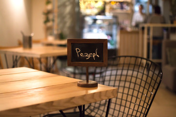 Reserved sign on a wooden table. The concept of restaurant and cafe service. Reserve space. Reserve mark. Preliminary reservation of a table in places of food. Reservation of a place for a date.