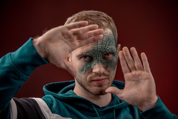 man with professional horror movie make-up green lizard on dark red background. lizard eye