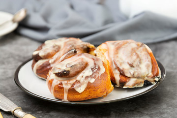 Cinnamon danish bun or cinnabons on dark background with coffee cup. Sweet homemade pastry.