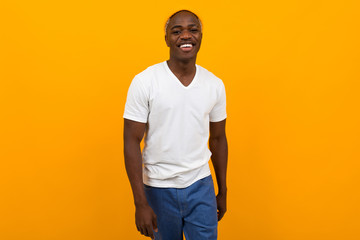 attractive african guy in a white t-shirt on a yellow background with copy space