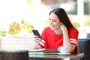 Happy student reading phone content in a coffee shop