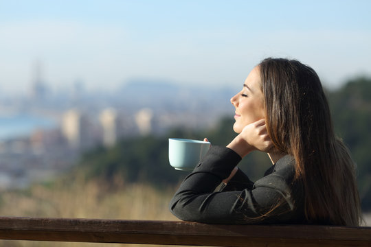 Businesswoman relaxing drinking coffee sitting on a bench
