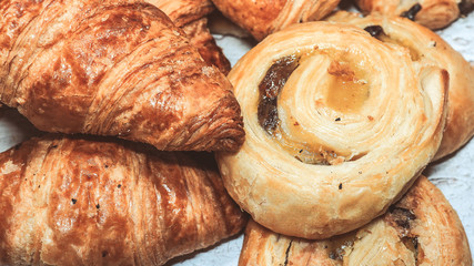Classic french butter croissant and raisin swirl, pain aux raisins from France. Closeup view on white wooden background