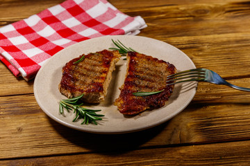 Grilled pork steaks with rosemary on wooden table