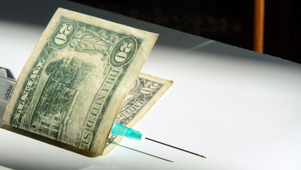 syringe wrapped in twenty dolar banknote. Concept - pharmacy, cost of medicines,