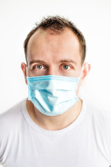 Vertical close-up portrait of scared caucasian man in blue medical mask on face, afraid of coronavirus. Health care in cold season. Scared expression