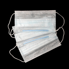 Isolated three disposable medical face masks against a black background