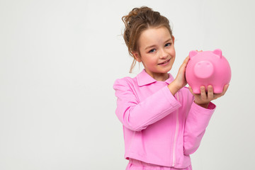 finance. portrait of a girl in a pink suit holding a piggy bank on a white background with copy space