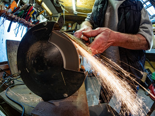 Home work shop and tool shed with grinder sharpening a chisel