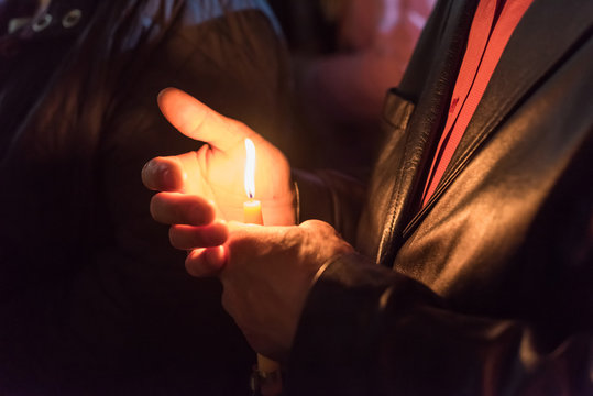 Closeup of people holding candle at night during church service