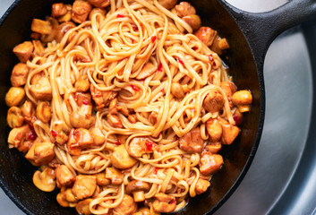 Homemade hot asian udon noodles with sweet and sour sauce, chicken and mushrooms in a pan Chinese food 