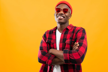 stylish smiling black african guy in red retro glasses on orange background with copy space