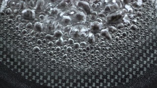 Slow motion : Top view Boiling water bubble in coating pan heating on electronic stove.