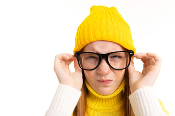 Happy teenager girl with red hair, hoody and hat with glasses isolated on white background