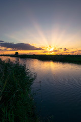 Beautiful landscape image of sunbeams over a lake at sunset