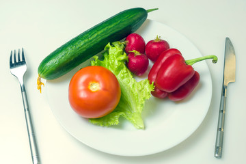 diet, healthy eating, food and weight loss concept - close up of fresh vegetables on a white plate with fork and knife.