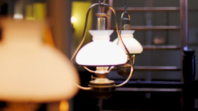 Three vintage lamps hanging from the ceiling in a row and swinging in an old 19th century wooden ship. Focus ramping with shallow depth of field.