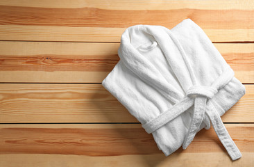 Clean folded bathrobe on wooden background, top view. Space for text
