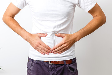 Young handsome man wearing white t-shirt over isolated background with hand on stomach because...