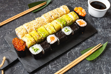 Various kinds of sushi served on black stone background