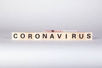 wooden cubes with text coronavirus and a syringe, vaccine, white background
