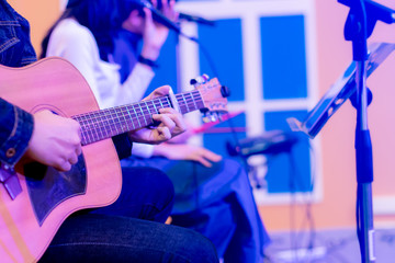 The male hand plays the guitar and women singing in the background.selective focus.