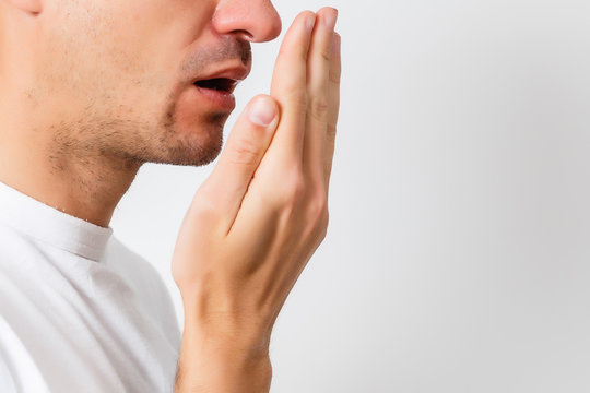 Bad breath. Halitosis concept. Young man checking his breath with his hand.