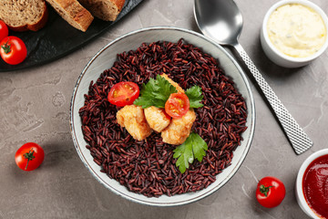 Tasty brown rice with chicken served on grey table, flat lay