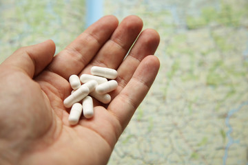 Hand holding white pills. Travel medication or drug trafficking concept image. 