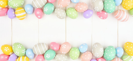 Pastel colored Easter Egg banner with double border against a white wood background. Above view with copy space.