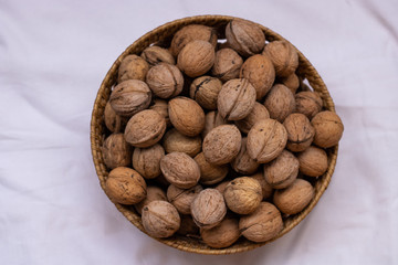 Small wicker basket filled with walnuts on a white background