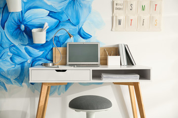 Stylish workplace with blue flowers painted on wall. Floral pattern in living room interior