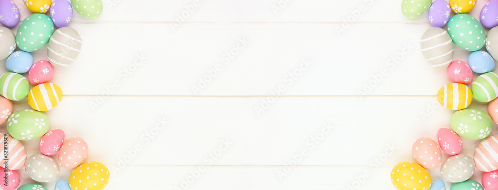 Poster pastel colored easter egg banner with double side border against a white wood background. top view w