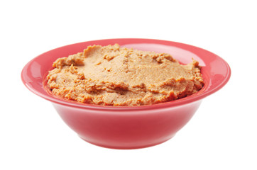 Plate with hummus - spread made from cooked, mashed chickpeas blended with tahini, lemon juice, garlic and dried tomatoes isolated on white background. Clipping path added