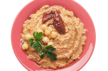 Flat lay view at hummus topped with beans, sun dried tomatoes and green coriander leaves isolated...