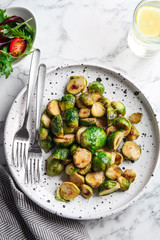 Delicious roasted brussels sprouts on white marble table, flat lay