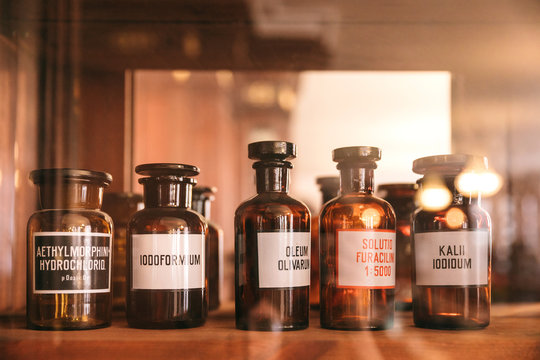 Dark Glass Potion Bottles With Medicines In An Old Pharmacy In A Wooden Cabinet