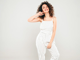 Fototapeta premium Portrait of beautiful smiling model with afro curls hairstyle dressed in summer hipster clothes.Sexy carefree girl posing in studio on gray background.Trendy funny and positive woman