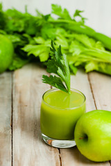Healthy food, vegan diet concept - glass of fresh green juice or smoothie with celery, apple, orange. Antioxidant fresh detox beverage with raw ingredients.  Close up, wooden background, copy space