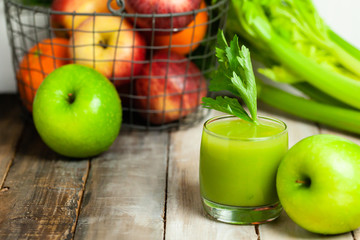 Healthy food, vegan diet concept - glass of fresh green juice or smoothie with celery, apple, orange. Antioxidant fresh detox beverage with raw ingredients.  Close up, wooden background, copy space